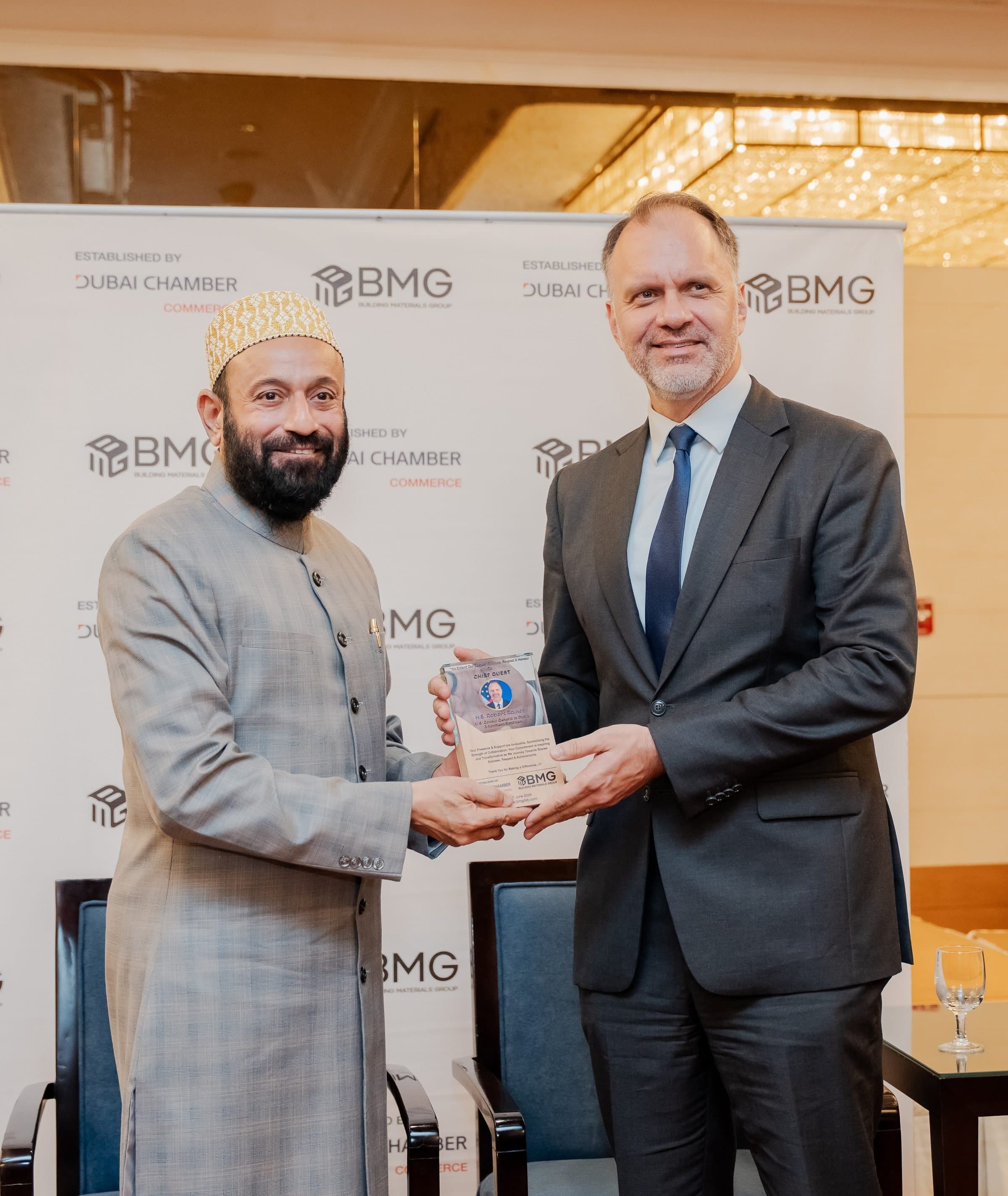 Two men holding an award between them in front of a BMG logo wall