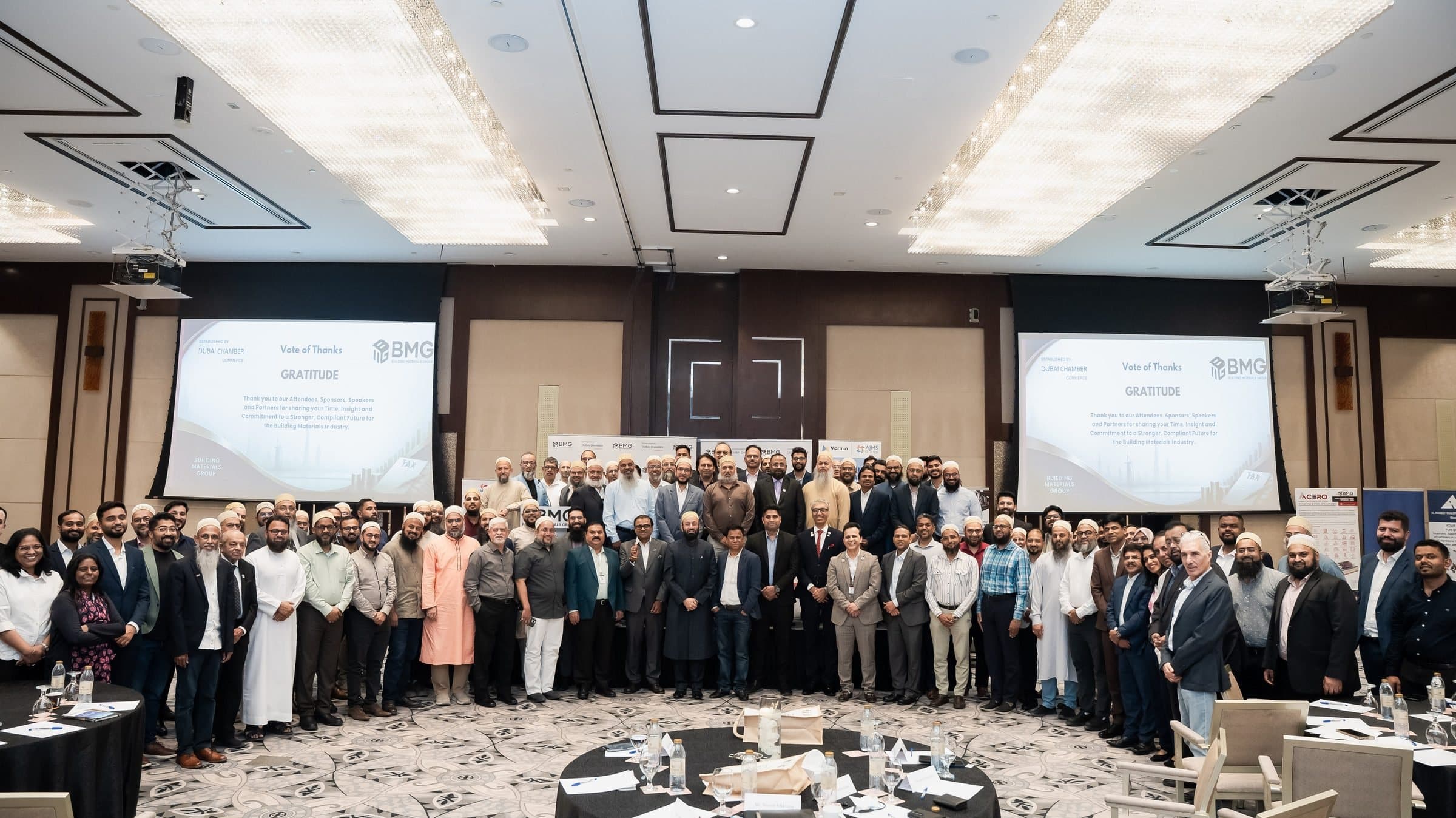 Very large group posing in a ballroom between two projection screens