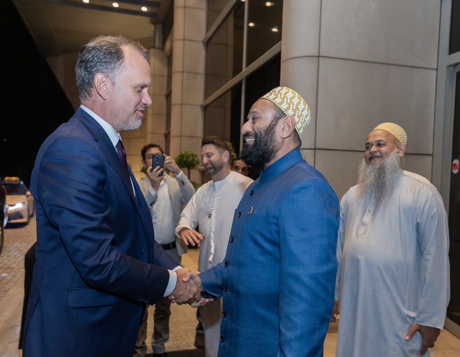 BMG Ramadan Suhoor 2026: Two men shaking hands at a night event while a third man in white looks on