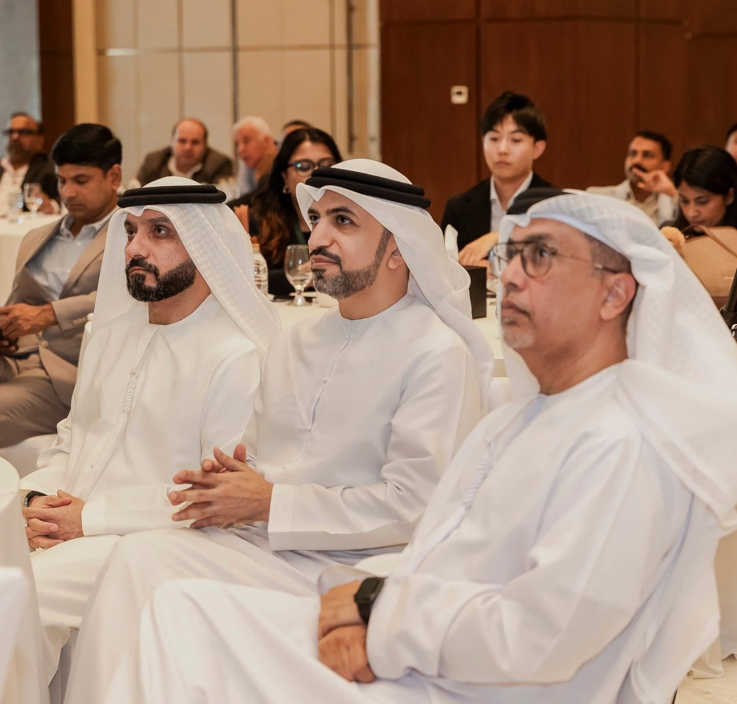 BuildConnect Ajman: Emirati guests in white kandura seated in the audience, looking toward the stage