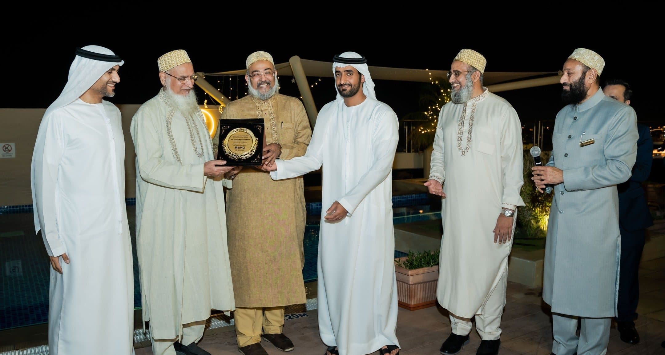 Ramadan Suhoor: Group of six men with a plaque on a rooftop terrace at night