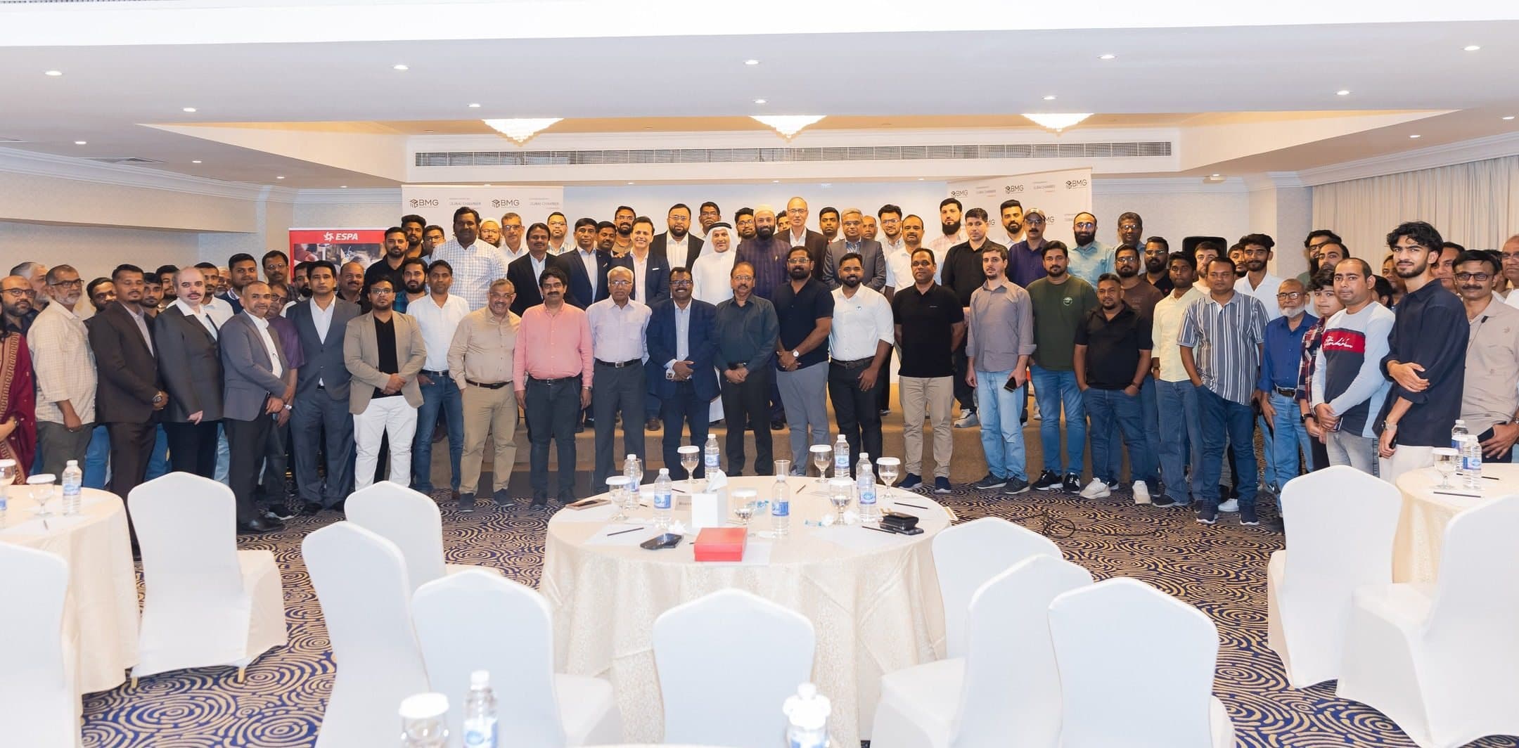 Wide group photo of a large crowd standing in a hotel hall
