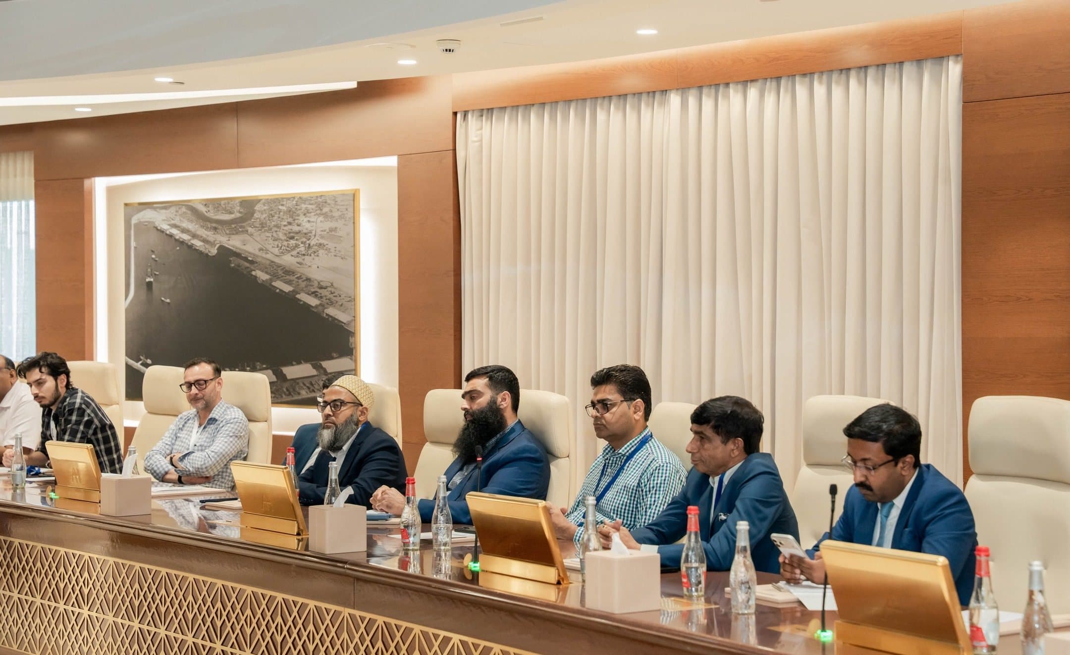 Members seated along a long curved boardroom table with microphones