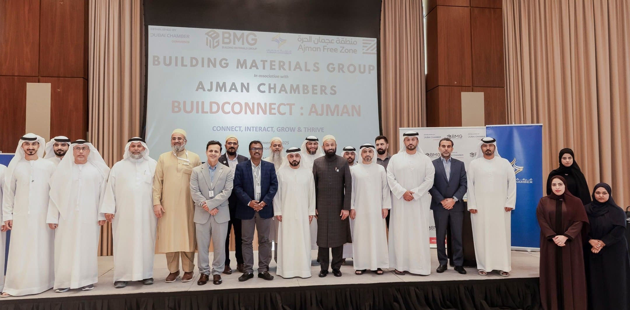 Large group on a stage below a screen reading Building Materials Group, Ajman Chambers, BuildConnect