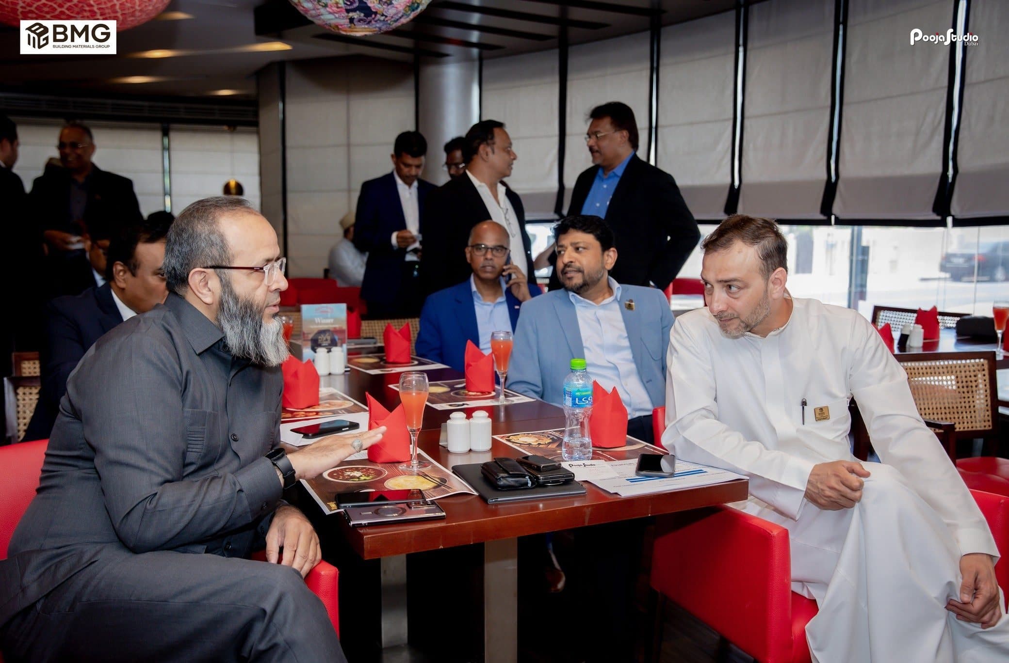 Members seated at restaurant tables with red chairs, talking over lunch